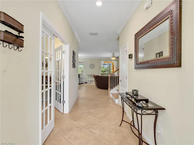 Hallway featuring ornamental molding, light tile patterned floors, and stairs