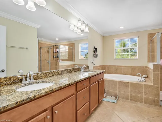 Bathroom with double vanity, healthy amount of natural light, a bath, light tile patterned floors, and ornamental molding