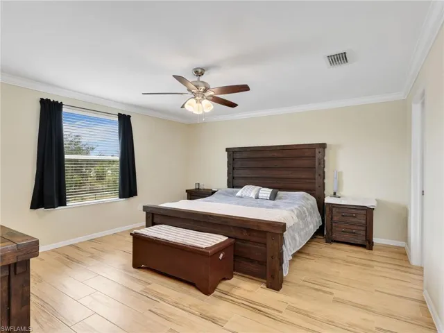 Bedroom with wood tiled floors, ornamental molding, and ceiling fan