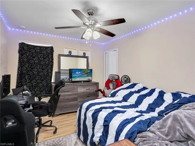 Bedroom featuring an office area, light wood finished floors, and a ceiling fan