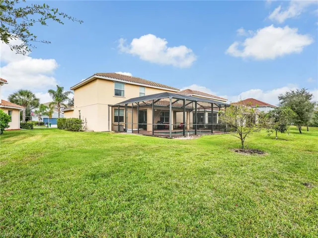 Back of property with a lanai, a sunroom, a yard, and a swimming pool