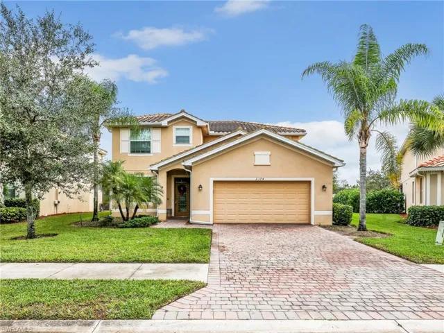 View of front of house featuring a front lawn, stucco siding, decorative driveway, and a garage