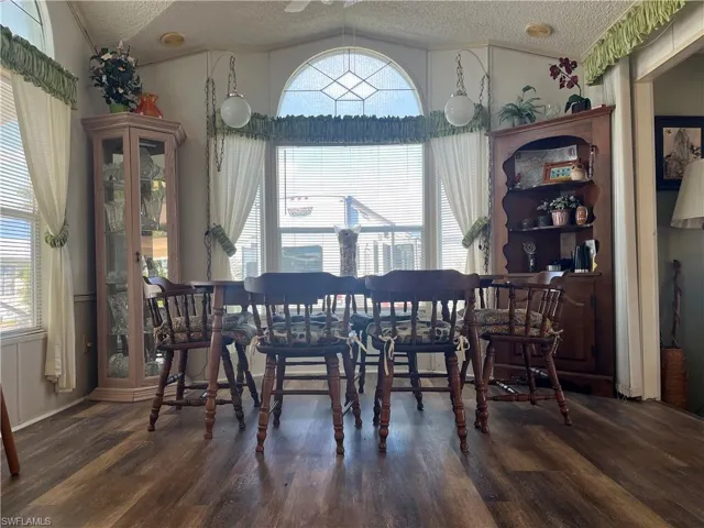 Dining room featuring a textured ceiling, vaulted ceiling, and dark wood-style flooring