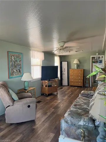 Living room with wood finished floors, a textured ceiling, and ceiling fan