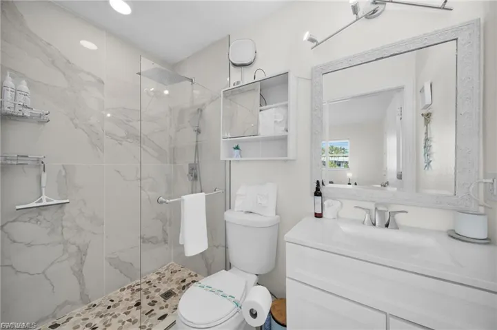 Walk-in shower with clear glass enclosure and marble-look tile surround