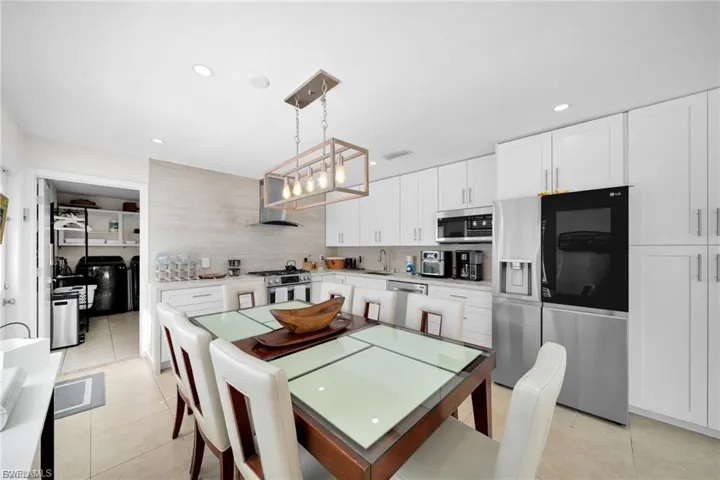 Modern kitchen featuring white cabinetry, stainless steel appliances, and a linear pendant light fixture