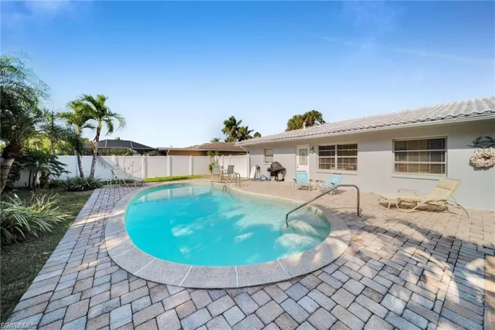 Outdoor swimming pool with integrated steps, surrounded by paver decking