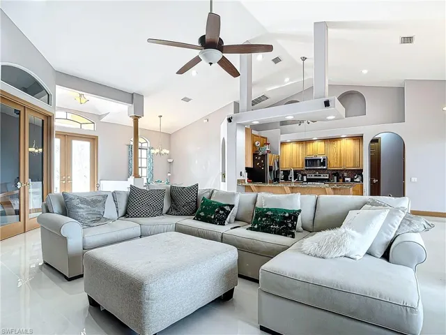 Living room featuring ceiling fan with notable chandelier, lofted ceiling, and french doors