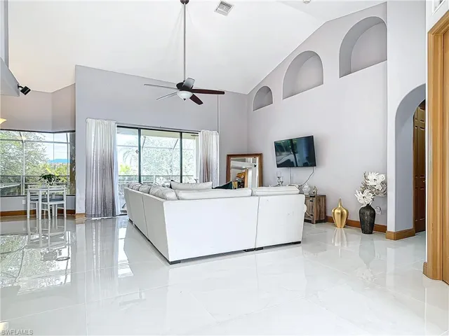 Living room featuring ceiling fan and a high ceiling