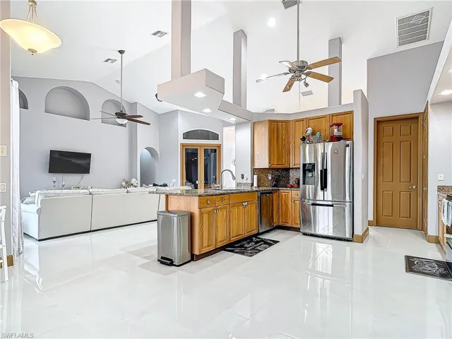 Kitchen with light stone countertops, stainless steel appliances, backsplash, kitchen peninsula, and decorative light fixtures