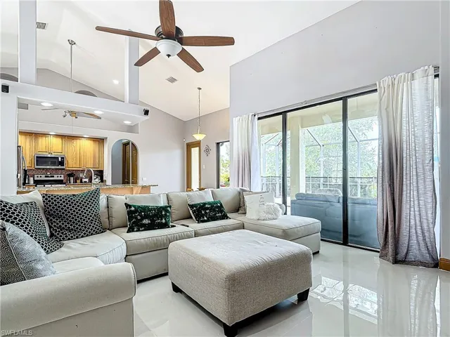 Living room with high vaulted ceiling, ceiling fan, and sink