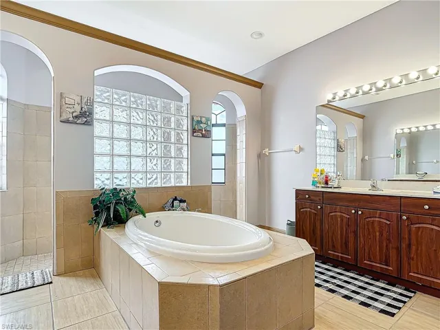 Bathroom featuring vanity, tile patterned flooring, and plus walk in shower