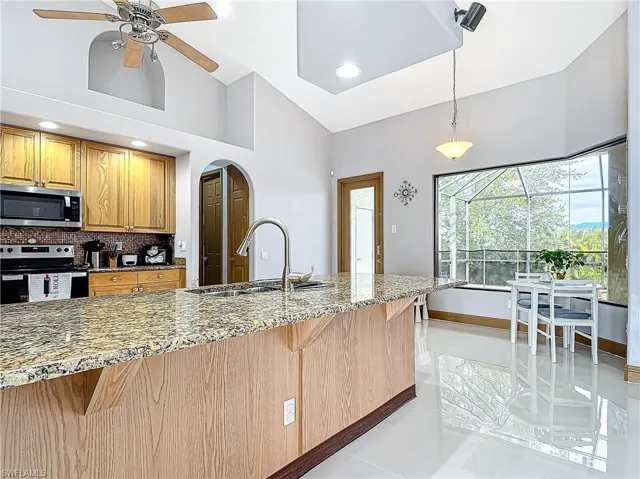 Kitchen with a kitchen breakfast bar, hanging light fixtures, sink, appliances with stainless steel finishes, and tasteful backsplash
