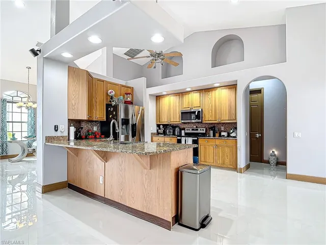 Kitchen with kitchen peninsula, decorative backsplash, a breakfast bar, and stainless steel appliances