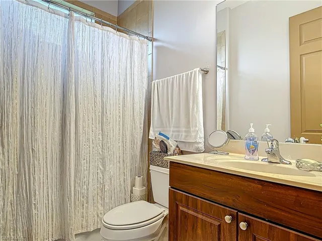 Bathroom featuring curtained shower, vanity, and toilet