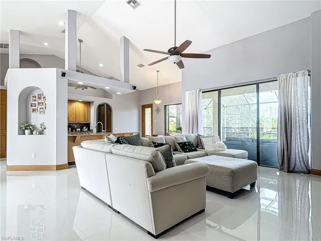 Living room featuring ceiling fan, sink, and high vaulted ceiling