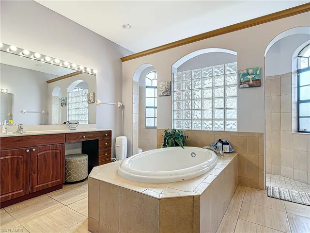 Bathroom with tile patterned flooring, vanity, and plus walk in shower