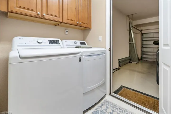 Washroom featuring washer and dryer, cabinet space, and concrete floors