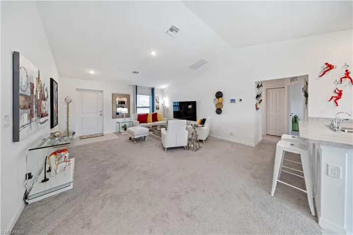 Living area featuring vaulted ceiling, light carpet, and recessed lighting