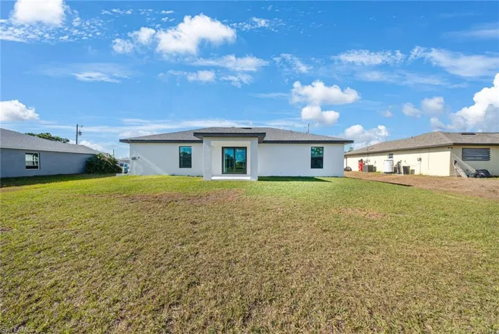 Back of property featuring stucco siding and a yard