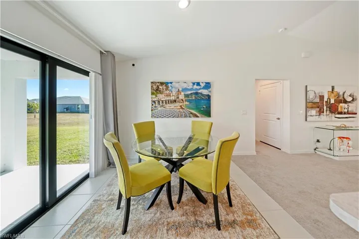 Carpeted dining room featuring vaulted ceiling and tile patterned floors