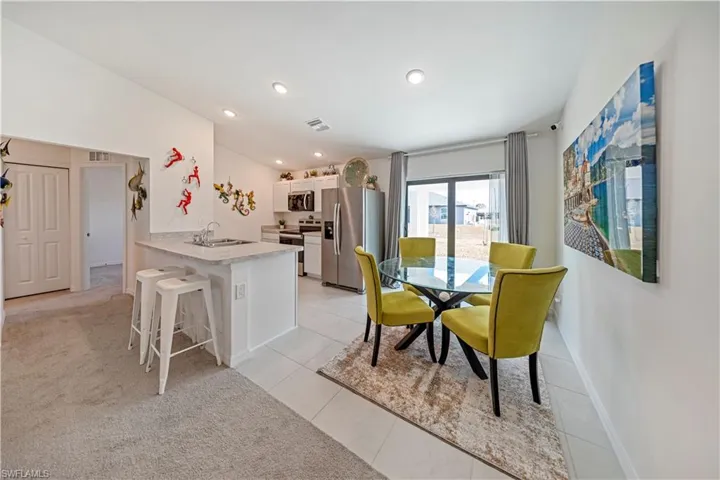 Dining space with vaulted ceiling, light colored carpet, recessed lighting, and light tile patterned floors