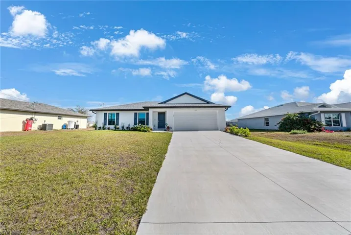 Ranch-style house featuring a front yard, driveway, a garage, and stucco siding