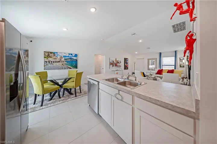Kitchen with open floor plan, stainless steel appliances, light countertops, lofted ceiling, and white cabinetry