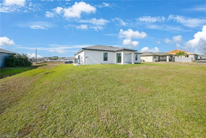 Rear view of property featuring stucco siding and a yard