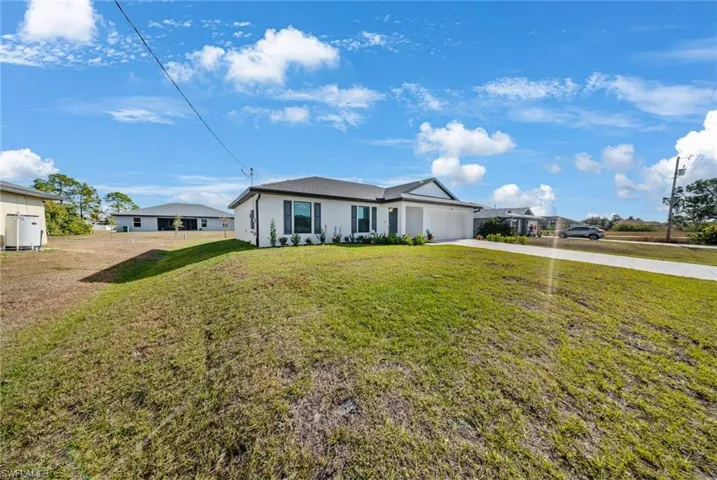 Ranch-style home with driveway, a front yard, an attached garage, and stucco siding