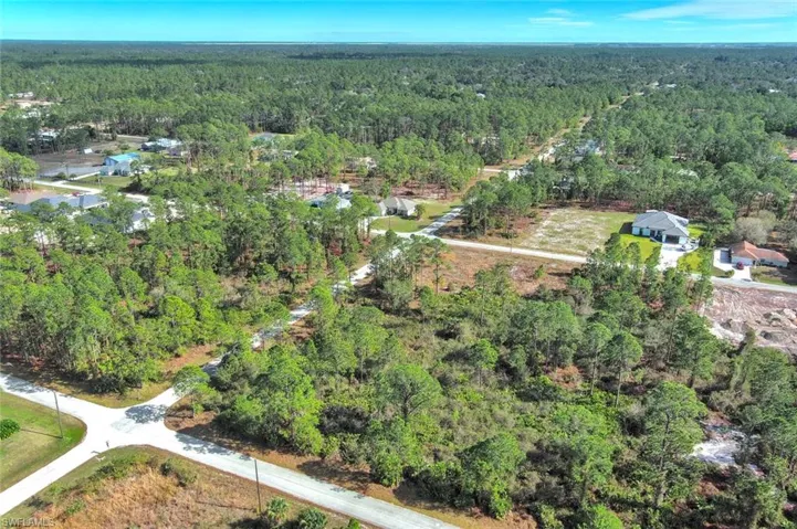 Aerial view of property and surrounding area featuring a forest