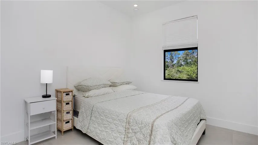 Bright interior space featuring a single window with blinds and a dark frame