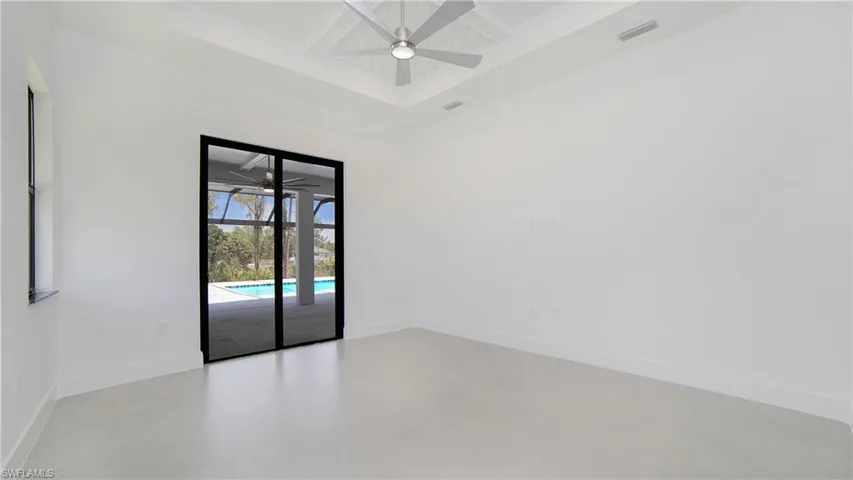 Spacious room featuring white walls, a coffered ceiling with a ceiling fan, and light-toned flooring
