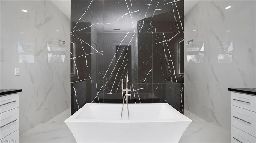 Freestanding soaking tub with a floor-mounted brushed nickel tub filler