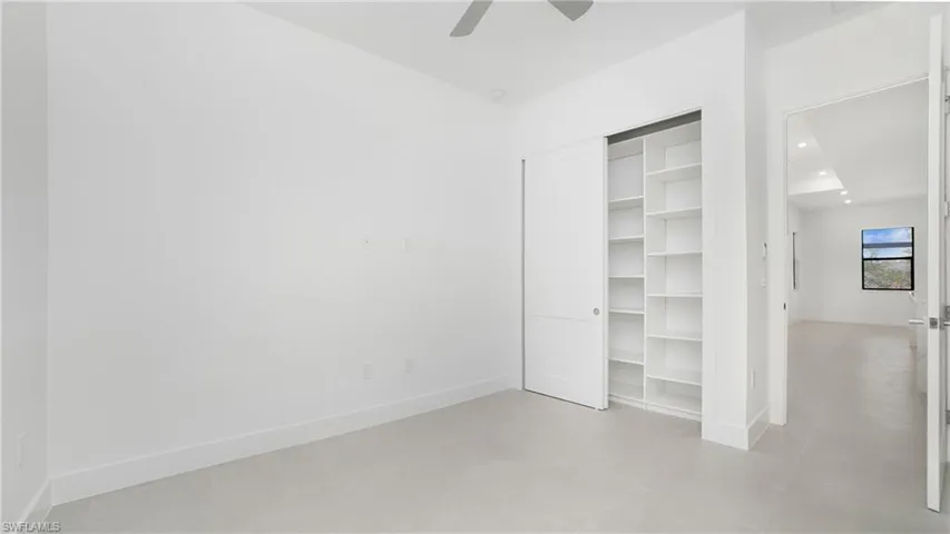 Recessed closet with integrated shelving, sliding panel doors, high ceilings, and light-toned flooring