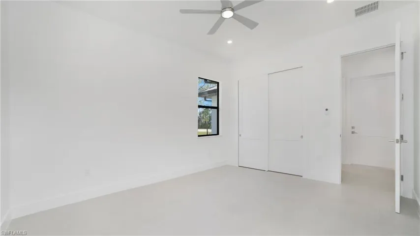 Spacious room featuring light-toned flooring, a window with black trim, a ceiling fan, recessed lighting, and a double sliding closet door