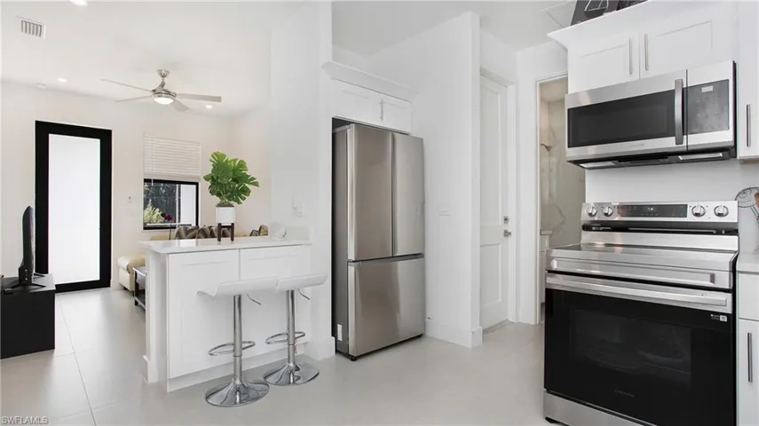 Contemporary kitchen featuring stainless steel appliances, white cabinetry, and light-toned flooring