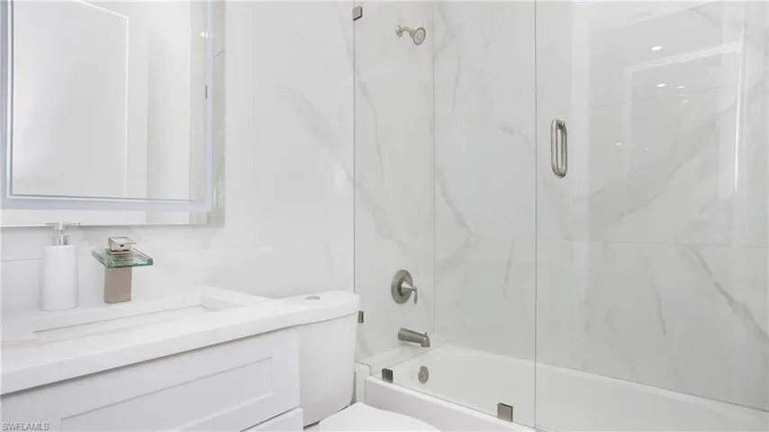 White bathroom featuring a glass-enclosed tub and shower combination