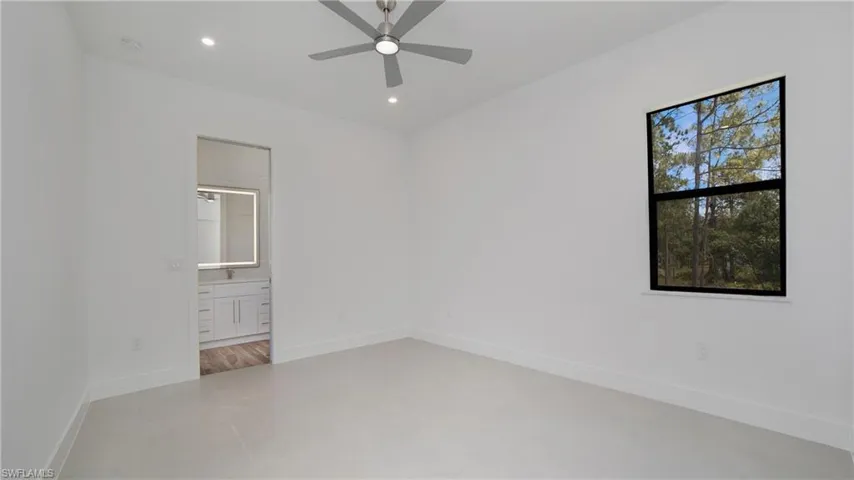 Bright room with light tile flooring, a window offering a wooded landscape, and a ceiling fan with integrated lighting