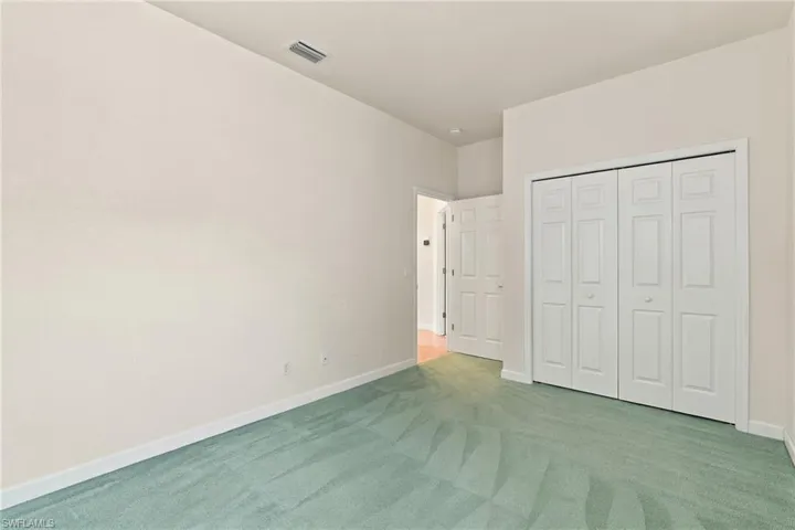 Room featuring neutral wall finishes, carpeted flooring, and white paneled interior doors, including a double-door reach-in closet