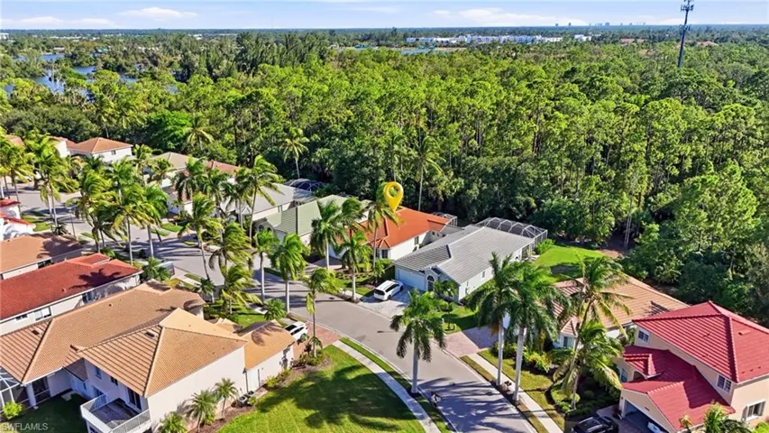 Aerial view of a residential property featuring a tile roof, paved driveway, two-car garage, and a screened-in lanai