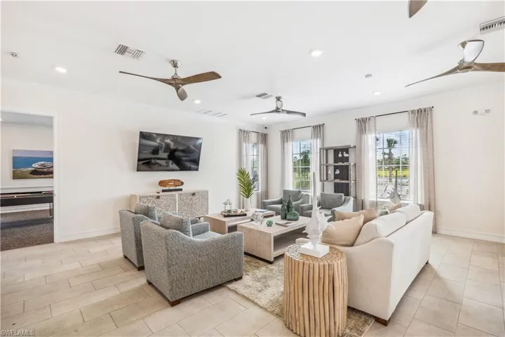 Tiled living room featuring ceiling fan and ornamental molding