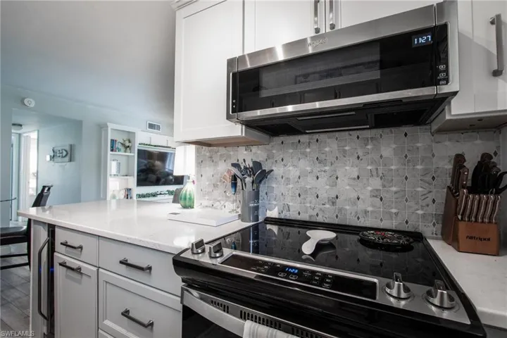 Kitchen featuring stainless steel appliances, white cabinets, hardwood / wood-style floors, and backsplash