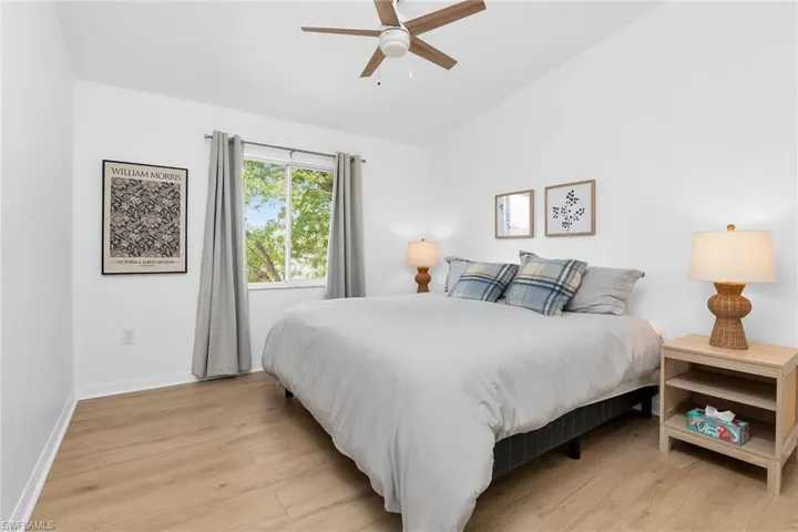 Bedroom with light wood-style flooring, vaulted ceiling, baseboards, and ceiling fan