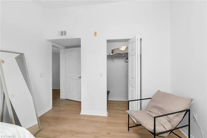 Bedroom with light wood-type flooring, baseboards, a walk in closet, and a closet