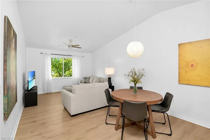 Dining room featuring vaulted ceiling, light wood finished floors, baseboards, a ceiling fan, and a chandelier