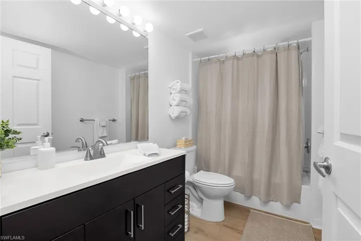 Full bathroom featuring vanity, toilet, wood finished floors, and shower / bath combo with shower curtain