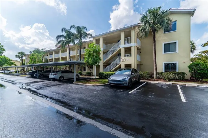 View of apartment building / complex featuring covered and uncovered parking and stairs