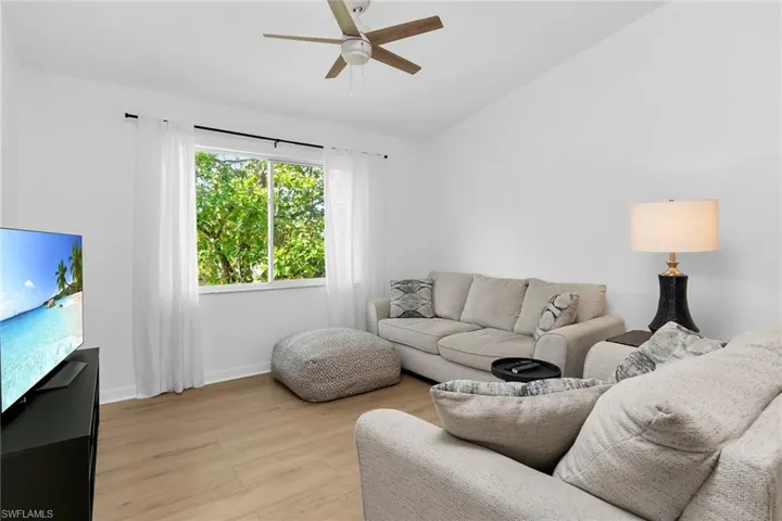 Living area with a ceiling fan, light wood finished floors, lofted ceiling, and baseboards