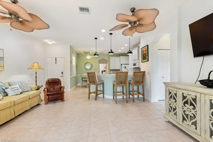 Kitchen featuring a kitchen breakfast bar, white appliances, light tile patterned flooring, and ceiling fan